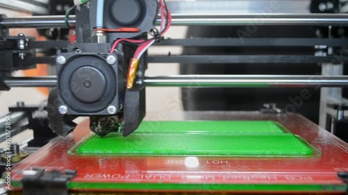 3D printer printing object. 3D printer printing an object from molten plastic on a work surface of 3D printer. 3D printer creating a model. Molten plastic flowing out of an extruder close-up