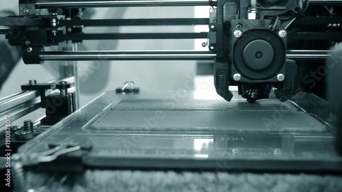 3D printer printing object. 3D printer printing an object from molten plastic on a work surface of 3D printer. 3D printer creating a model. Molten plastic flowing out of an extruder close-up