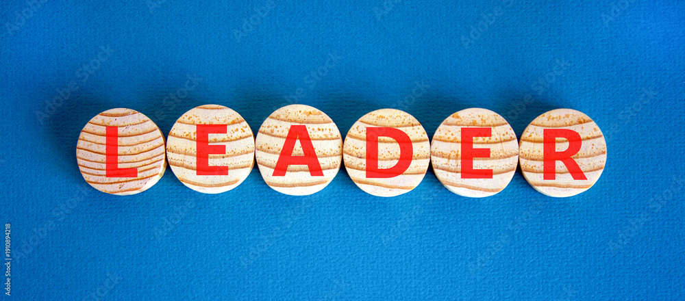 Fototapeta premium Leadership and leader symbol. Concept word Leader on beautiful wooden circles. Beautiful blue background. Business leader and leadership concept. Copy space.