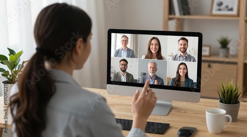 A woman participates in a virtual meeting on her computer in a modern office setting.