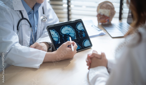 Doctor explaining brain MRI scan results on digital tablet.