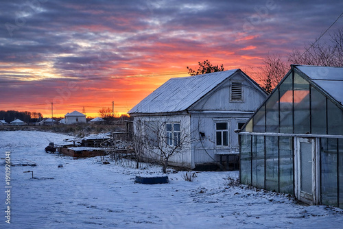 Cold Winter Countryside with Snowy Houses Under Dramatic Evening Sky