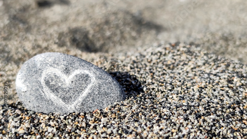 Heart symbol carved on a stone resting in fine sand at a beach during daylight