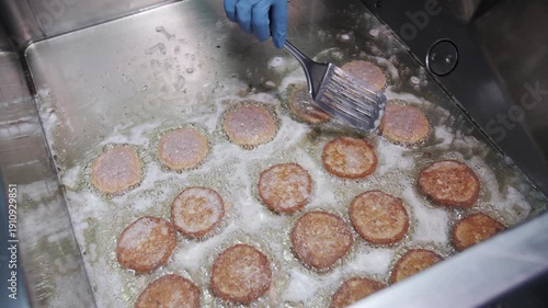 Industrial kitchen frying multiple pancakes in hot oil.