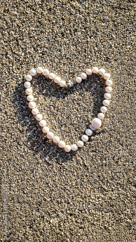 Concept of love and health. Heart shape made from a string of beads on sandy ground during daytime inviting thoughts of love and connection