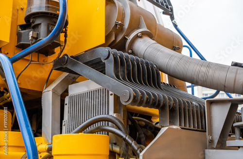 Canvas Print Close-up of industrial hydraulic oil cooler and protective steel grille on yellow heavy machinery
