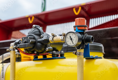 Foto Close-up of a pressure regulator gauge and diaphragm pump on a yellow agricultural sprayer