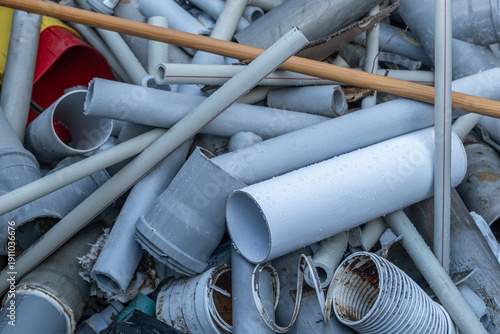Pile of discarded gray plumbing tubes and plastic pipes