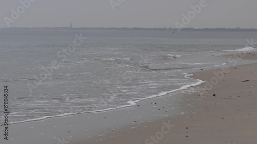 The beach is empty and the water is calm. The sky is overcast and the beach is covered in sand