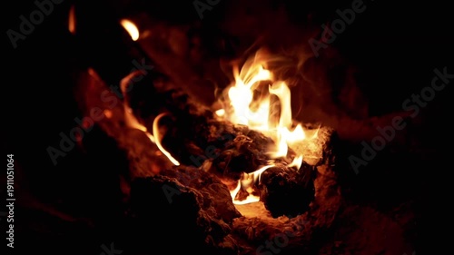 Firewood burns intensely in the night, casting a warm and flickering glow. Flames create a mesmerizing dance of light and shadow. Perfect for projects about nature, survival.