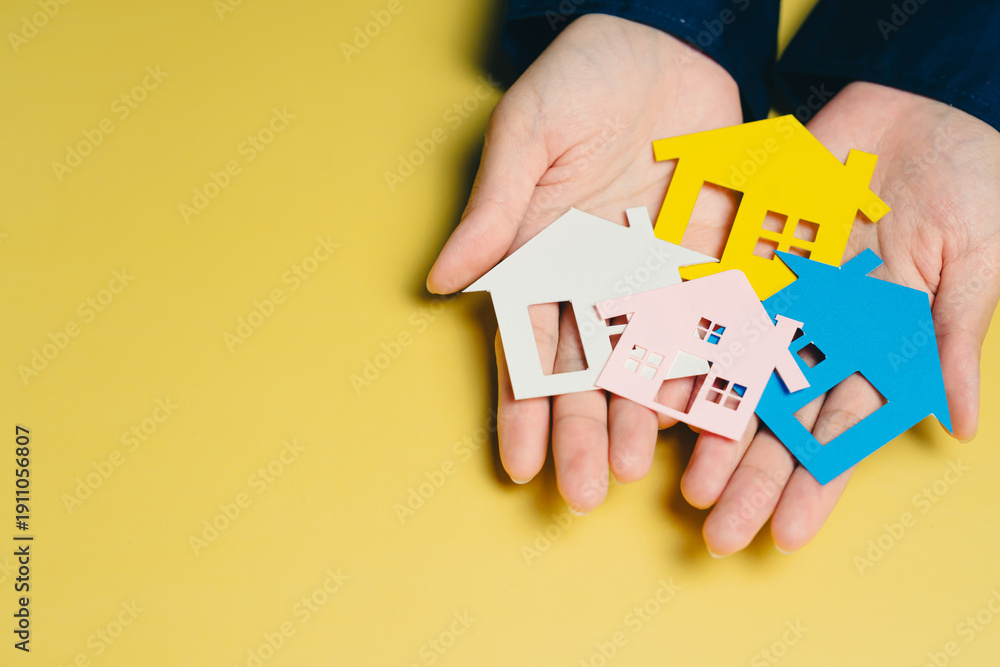Fototapeta premium New house concept. Colorful house shapes held in hands symbolize home ownership and real estate investment. This conveys warmth and security