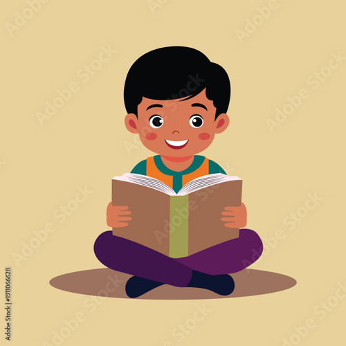 A young boy sitting cross legged reading a book with a smile