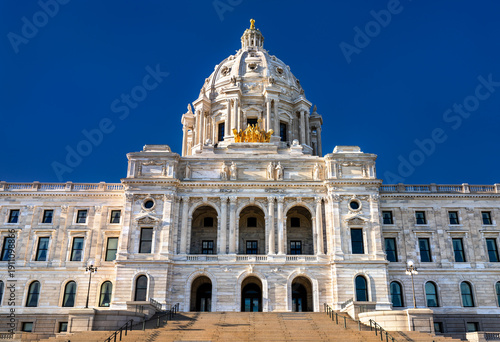 Minnesota State Capitol building stands in Saint Paul, USA. Renaissance Revival architecture features a white marble dome and golden quadriga statue under a blue sky