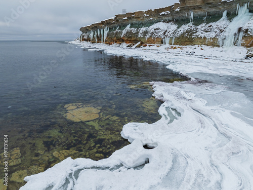 High angle drone view of the Baltic Sea starting to freeze near the steep limestone cliffs of the Pakri peninsula.