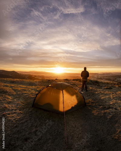 A man wild camping in the Peak District of England during an amazing sunrise