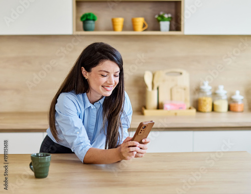 Wallpaper Mural Portrait of a healthy young woman businesswoman enjoying morning, drinking coffee  in kitchen and talking and using a smart phone at home Torontodigital.ca