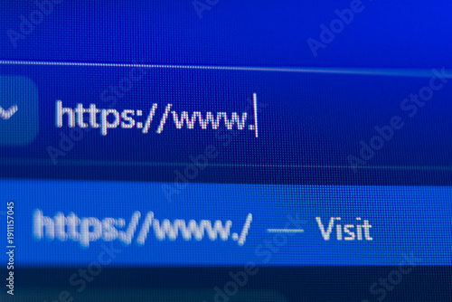 Close up of a web browser search bar on a blue pixelated screen showing a secure https prefix with a flashing cursor, representing web navigation, internet connectivity, and cyber security.