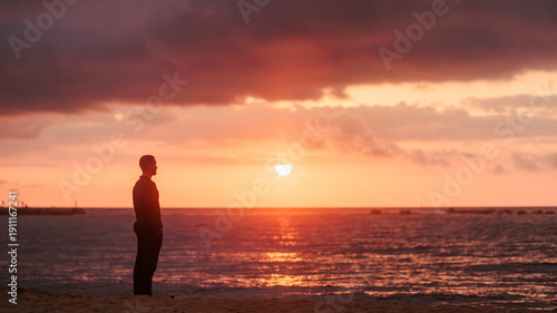 Man finding solitude on beach watching sunset
