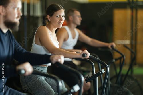 Картината върху платно Sportive young woman doing air bike exercises in well-equipped gym during traini