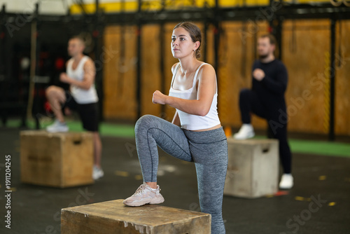 Fotografie Determined young girl stepping on box in sports hall during crossfit workout