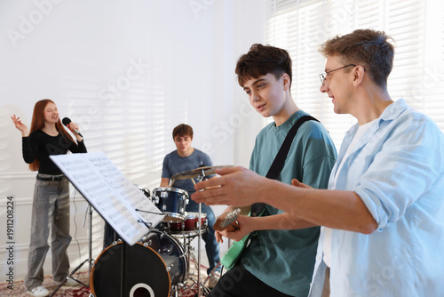 Foto Teenage band practicing their performance with music teacher indoors