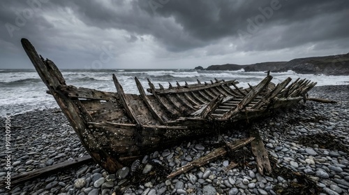 Decaying wooden longboat hull on a pebble beach