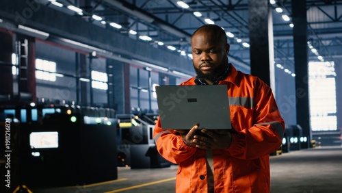 фотографія Industrial staff member oversees assembly work in a warehouse while using laptop to support professional supervision and ensure safe and efficient steel manufacture and production flow