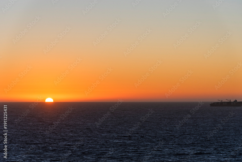 Fototapeta premium Dramatic sunset sky above the Pacific Ocean with vessel silhouetted against the horizon.