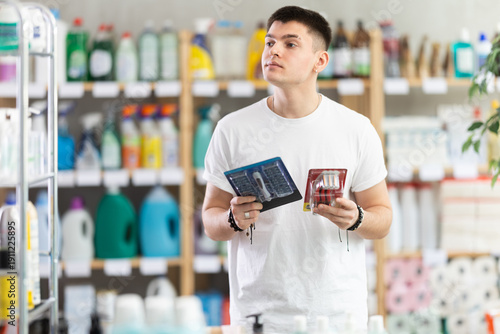 Obraz na plátne Young man buyer chooses shaving razor in household chemicals store