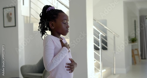 African schoolgirl placing hands, breathing slowly for calm by stairs wearing pink top