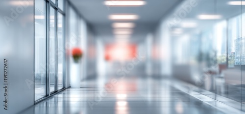 Modern blurred office corridor with glass walls and white vase with red flowers, sleek minimalist business interior space