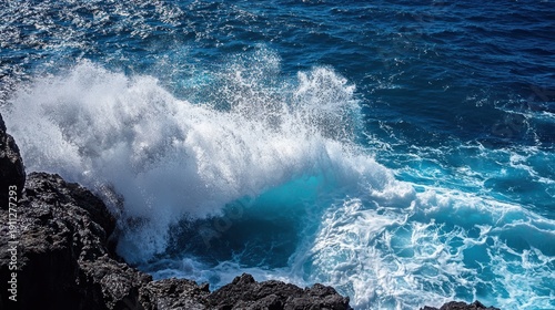 The powerful ocean waves crash against the dark, rocky shoreline, creating a dramatic display of nature's raw energy and beauty with a burst of white foam and spray
