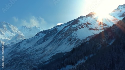 Snow covered mountain range landscape under clear blue sky with sunlight