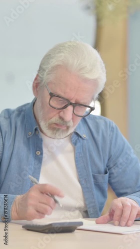 Old Man Doing Calculation Work on Documents, vertical video