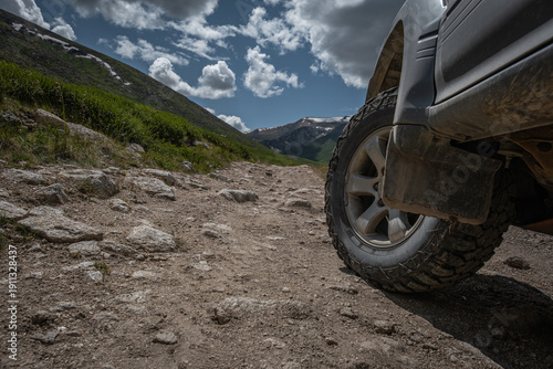 Close up of off-road vehicle wheel on rocky mountain road in Mongolia, SUV tire on rough terrain under cloudy sky, adventure travel and 4x4 expedition concept, extreme driving
