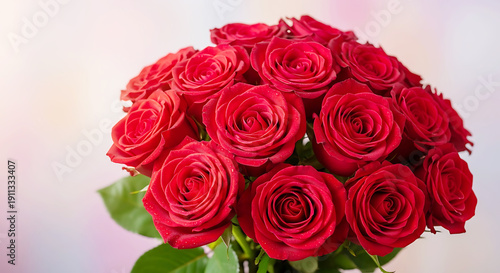 Lush bouquet of vibrant red roses with green leaves on a soft pastel bokeh background for romantic Valentine's Day or wedding anniversary
