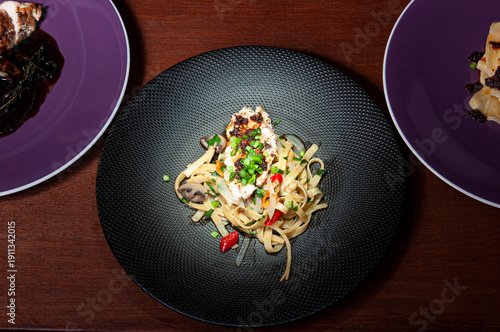 Spagetti aglio olio z papryczkami chili na czarnym talerzu stojącym na stole