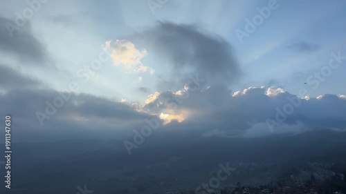 Cinematic time-lapse of crepuscular rays (Tyndall effect) shining through moving clouds over a mountain valley. Divine and peaceful atmosphere. 1080p.