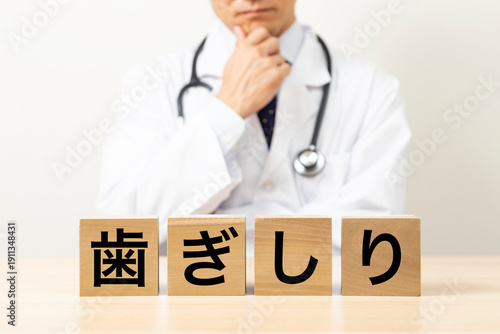 「歯ぎしり」と書かれたブロックと悩む医師