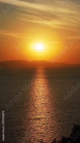 A beautiful orange sunset in the sea and over the ocean horizon with sun reflection on water waves and clouds in a nature beach landscape