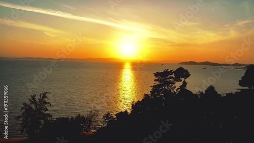 Beautiful orange sunset over the sea and lake landscape with a vibrant sun reflection on the water waves under a summer sky at dusk