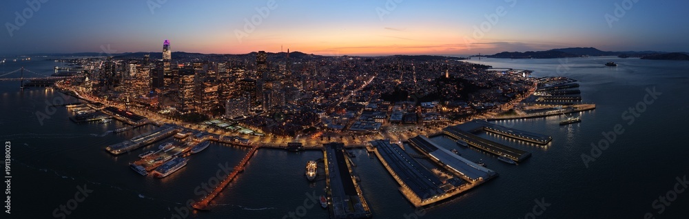 Fototapeta premium San Francisco downtown skyline and Embarcadero waterfront at blue hour, Bay Bridge and Ferry Building aerial view. g.