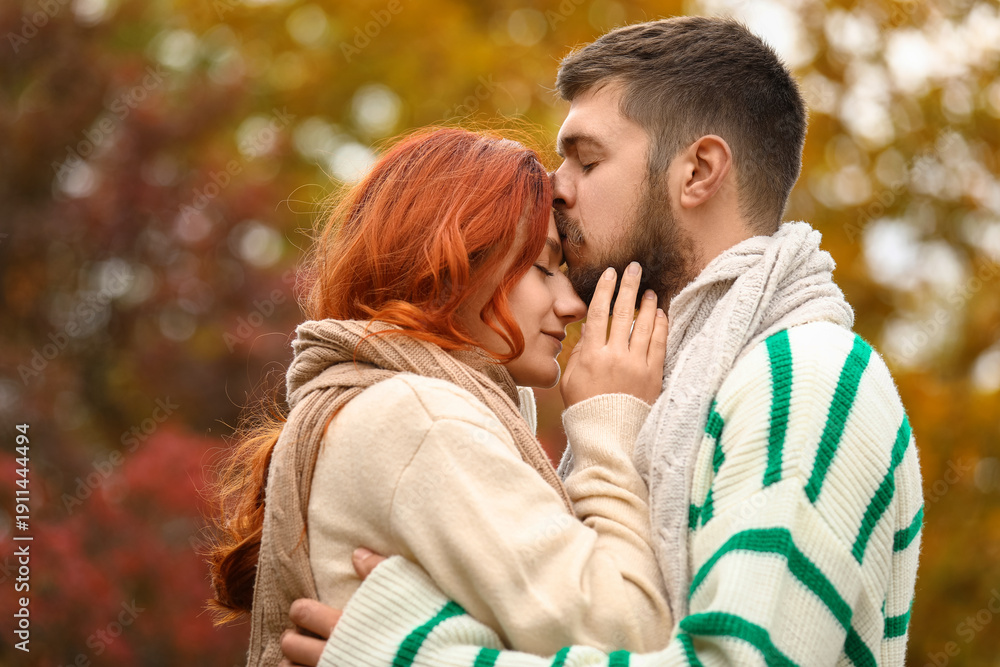 Fototapeta premium Handsome young man kissing forehead of his girlfriend at autumn park