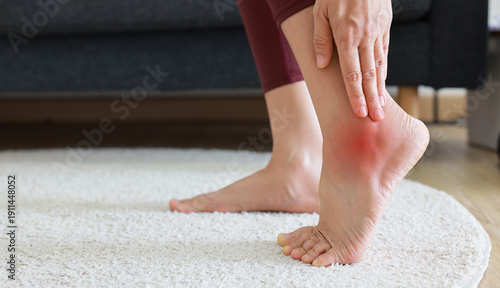 Tableau sur toile Woman standing and massaging her painful heel with red highlight