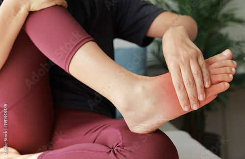Konstfotografi Woman massaging her painful foot with red highlight on sole and instep