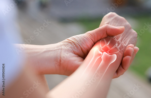 Принти на полотні Woman massaging her painful wrist with anatomical bone illustration and red highlight