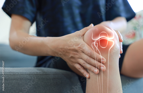 Fotografía Woman massaging her painful knee with anatomical joint and bone illustration