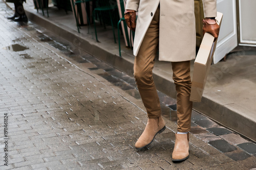 Картината върху платно Stylish man carrying a cardboard box while walking along a wet cobblestone stree