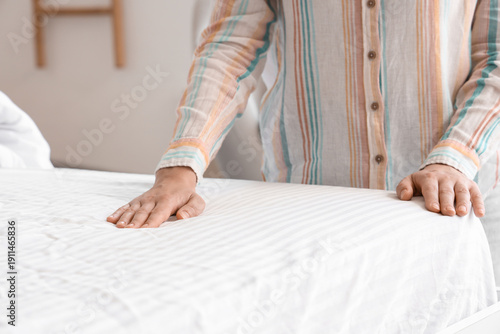 Young woman making bed in l...
