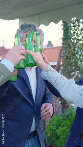 Mature friends dancing and toasting with beer bottles on a rooftop party